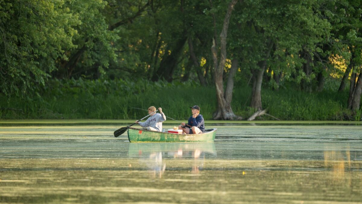 Kanu mit Angelausrüstung auf einem ruhigen See bei Morgenlicht