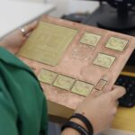Leiterplatten-Layout auf einem Bildschirm neben einer bestückten Platine
