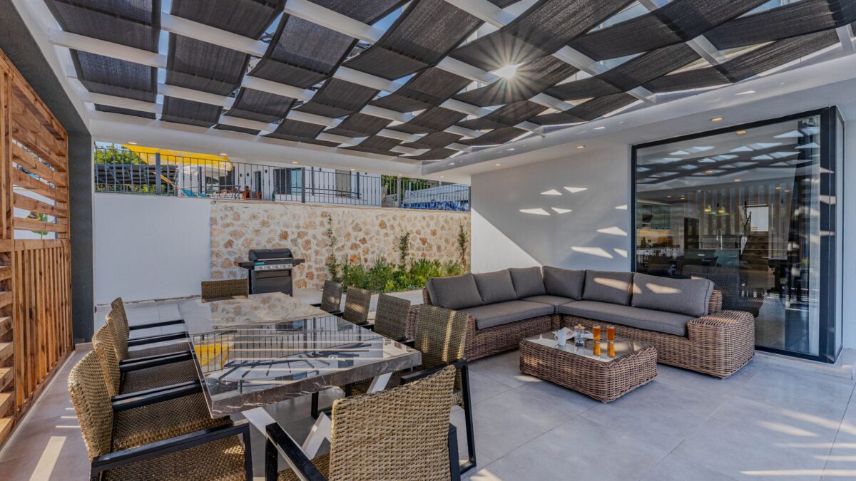 Moderne Terrassenüberdachung aus Glas und Aluminium über einem Sitzplatz im Garten